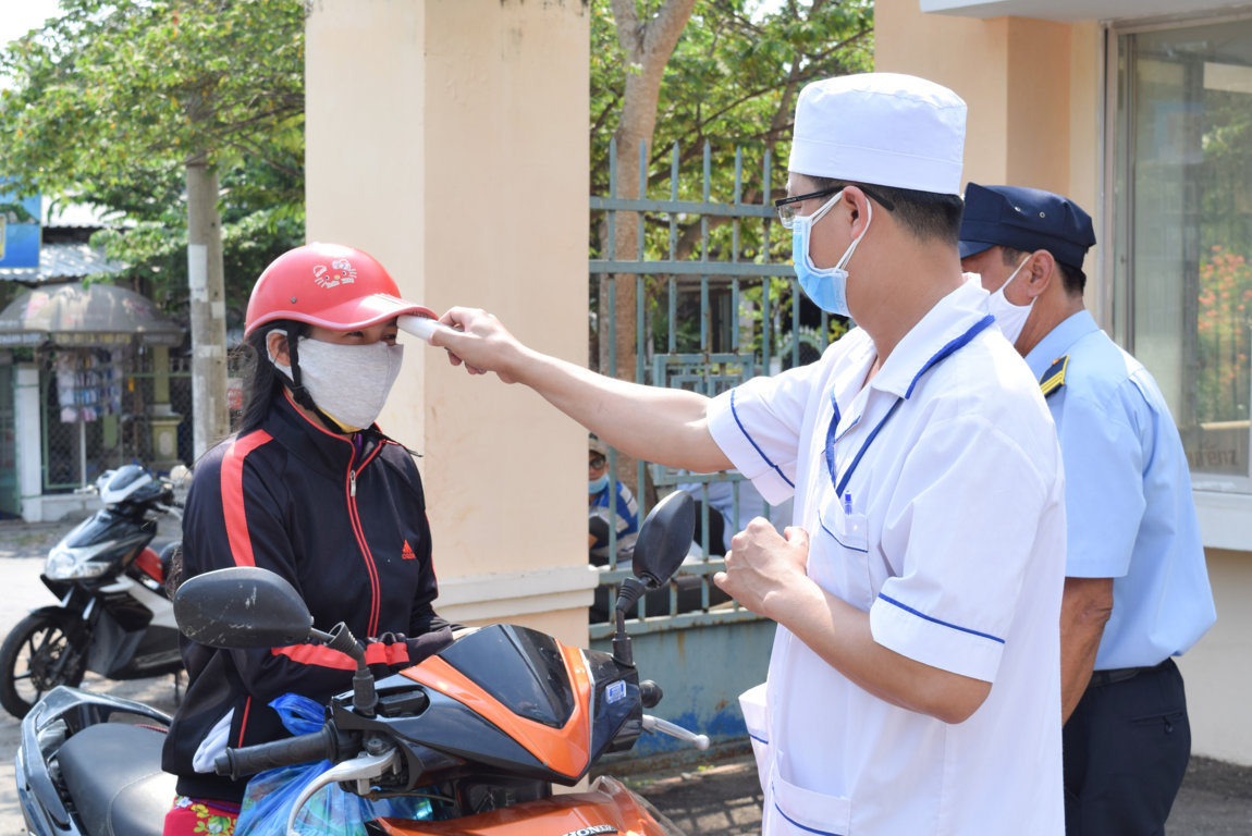 Thực hiện kiểm tra thân nhiệt người dân khi đến khám tại Trung tâm Y tế huyện Phong Điền. Ảnh: Thiên Thanh.