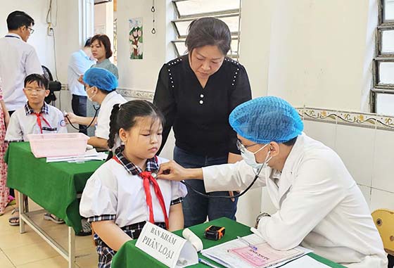 Trẻ được kiểm tra tiền sử tiêm chủng, khám sàng lọc trước tiêm vắc xin phòng bệnh sởi, tại điểm tiêm trường Tiểu học Kim Đồng, phường An Khánh, quận Ninh Kiều.